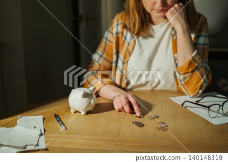 Cost of living crisis concept with worried woman counting coins at home, copy space Cost of living crisis concept with worried woman counting coins at home, copy space 140148319