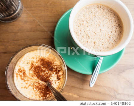 Two coffee drinks on a wooden table Two coffee drinks on a wooden table 140148362