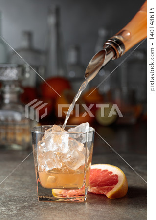 Grapefruit juice is poured into a glass with ice. Grapefruit juice is poured into a glass with ice. 140148615