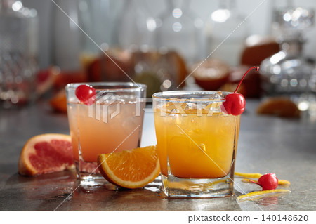 Cocktails with ice, grapefruit juice, and orange juice garnished with maraschino cherry. Cocktails with ice, grapefruit juice, and orange juice garnished with maraschino cherry. 140148620