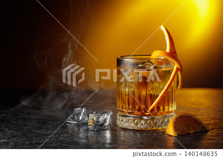 Whiskey with ice in a fogged up glass on a black stone table. 140148635