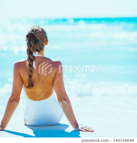Young woman sitting at seaside. rear view Young woman sitting at seaside. rear view 140148699