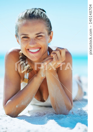 smiling young woman laying on beach smiling young woman laying on beach 140148704