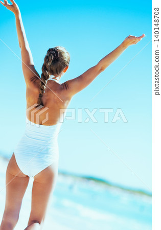 Young woman rejoicing on beach. rear view Young woman rejoicing on beach. rear view 140148708