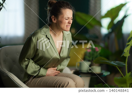 Woman in Pain Resting in a Modern Armchair Woman in Pain Resting in a Modern Armchair 140148841