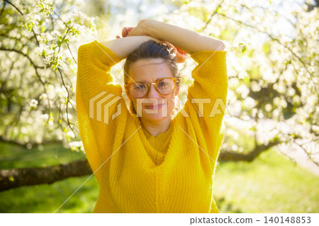 Joyful Woman with Raised Arms in Spring Blossom Park 140148853