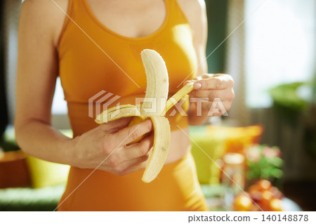 Fit Woman Peeling a Fresh Banana for a Snack Fit Woman Peeling a Fresh Banana for a Snack 140148878