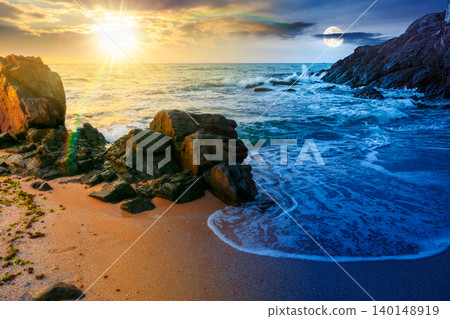 huge stones on the sandy beach. day meet night. wonderful holiday season background at the sea at twilight. sun and moon over clouds on the epic sky above horizon. view of waves washing the shore huge stones on the sandy beach. day meet night. wonderful holiday season background at the sea at twilight. sun and moon over clouds on the epic sky above horizon. view of waves washing the shore 140148919