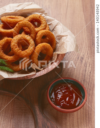 Deep fried onion rings, appetizer, with tomato sauce, on a wooden table, no people, favorite dish, Deep fried onion rings, appetizer, with tomato sauce, on a wooden table, no people, favorite dish, 140148942