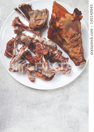 Roast pork head, with remnants of bones and meat, on a white platter, no people, close-up, Roast pork head, with remnants of bones and meat, on a white platter, no people, close-up, 140148945