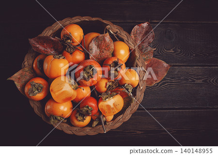 fresh persimmon in a basket, with leaves, top view, no people, fresh persimmon in a basket, with leaves, top view, no people, 140148955