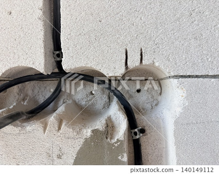 Wiring the house. Construction wall made from white aerated concrete blocks. 140149112