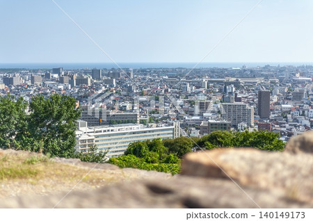 A panoramic view of Yonago city and the horizon of the Sea of Japan from the castle tower base of Yonago Castle ruins, over the rugged stone walls in the foreground (Yonago City, Tottori Prefecture). 140149173