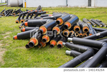 Stacked district heating pipes with polyurethane insulation on grass, utility network renovation materials closeup Stacked district heating pipes with polyurethane insulation on grass, utility network renovation materials closeup 140149264
