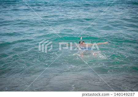 Caucasian man wearing a full face snorkeling mask swims in the Red Sea near Sharm El Sheikh Egypt with turquoise water around him. Beach sea vacation travel resort lifestyle Caucasian man wearing a full face snorkeling mask swims in the Red Sea near Sharm El Sheikh Egypt with turquoise water around him. Beach sea vacation travel resort lifestyle 140149287