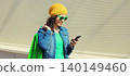 Beautiful happy young woman holding phone with colorful shopping bag 140149460