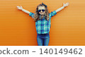 Happy cheerful kid girl with curly hair, joyful little child having fun in the city on orange wall 140149462