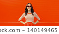 Beautiful happy smiling young brunette woman posing in red heart shaped sunglasses, skirt in city 140149465