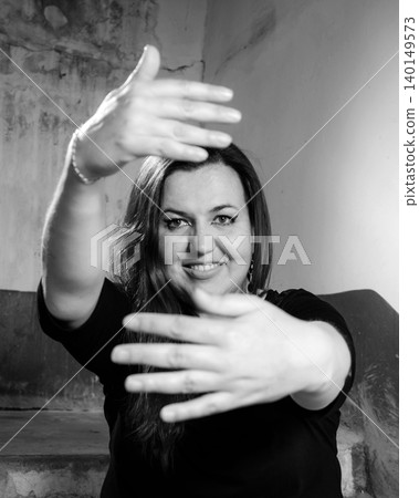 woman smiles into the lens, stretching her arms forward and creating a frame with her palms woman smiles into the lens, stretching her arms forward and creating a frame with her palms 140149573