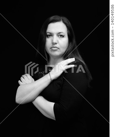 woman with her arms crossed over her chest placed her palm on her shoulder on a dark background woman with her arms crossed over her chest placed her palm on her shoulder on a dark background 140149586
