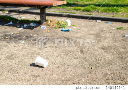 公園長椅周圍散落著紙杯和大量煙頭。 140150641