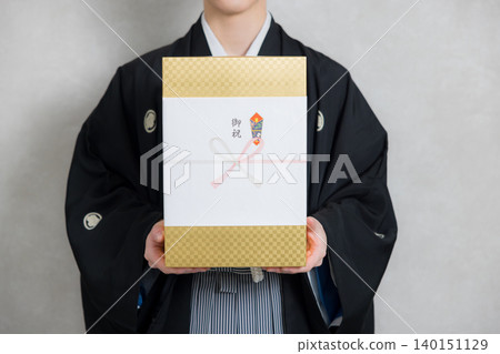 A young man in a kimono holding a congratulatory gift. A young man in a kimono holding a congratulatory gift. 140151129