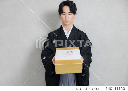 一位穿著和服的年輕男子手捧祝賀禮物。 一位穿著和服的年輕男子手捧祝賀禮物。 140151130