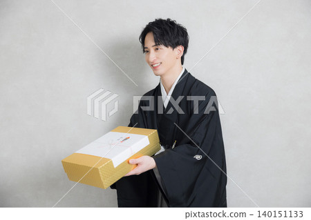 A young man in a kimono holding a congratulatory gift. A young man in a kimono holding a congratulatory gift. 140151133