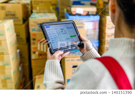 A woman operating a tablet in a warehouse. A woman operating a tablet in a warehouse. 140151390