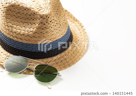 A straw hat and sunglasses against a white background. 140151445