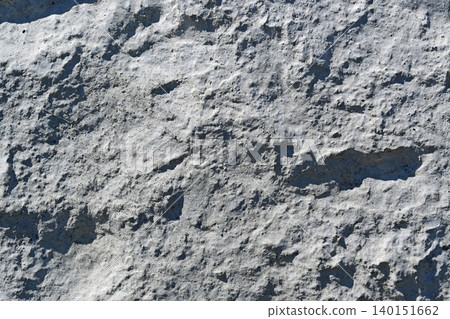 A textured concrete wall with a rough surface; an inorganic background material with unevenness and shadows. A textured concrete wall with a rough surface; an inorganic background material with unevenness and shadows. 140151662