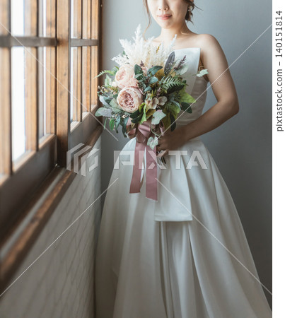 Bride in a wedding dress holding a bouquet (window, light) 140151814