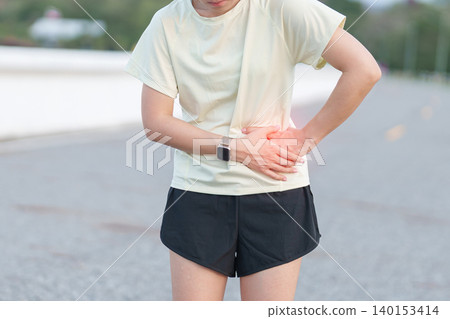 Adult runner suffering from side stitch and waist pain during exercise. woman holding his side due to sharp abdominal cramp or muscle ache while running. Sports injury and healthcare concept Adult runner suffering from side stitch and waist pain during exercise. woman holding his side due to sharp abdominal cramp or muscle ache while running. Sports injury and healthcare concept 140153414