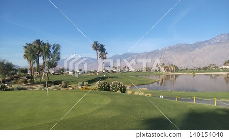 A golf course with a pond and mountains adorned with flowers and cacti. A golf course with a pond and mountains adorned with flowers and cacti. 140154040