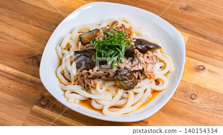 A photo of a chilled udon noodle dish with eggplant and pork, topped with shiso leaves, perfect for summer. 140154334