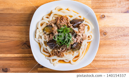 A photo of a chilled udon noodle dish with eggplant and pork, topped with shiso leaves, perfect for summer. A photo of a chilled udon noodle dish with eggplant and pork, topped with shiso leaves, perfect for summer. 140154337