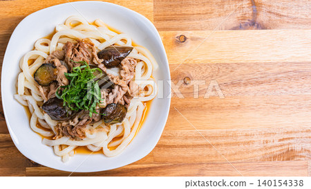 A photo of a chilled udon noodle dish with eggplant and pork, topped with shiso leaves, perfect for summer. 140154338