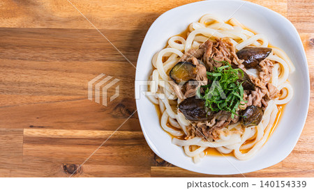 A photo of a chilled udon noodle dish with eggplant and pork, topped with shiso leaves, perfect for summer. A photo of a chilled udon noodle dish with eggplant and pork, topped with shiso leaves, perfect for summer. 140154339