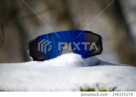 Sport performance sunglasses with mirrored blue lenses resting on snow Sport performance sunglasses with mirrored blue lenses resting on snow 140155279
