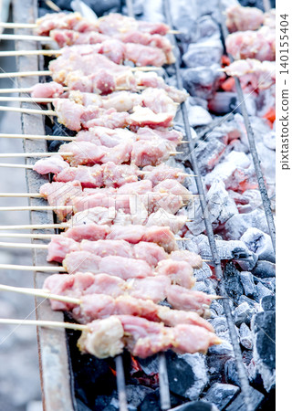 Raw meat skewers grilling on charcoal grill Raw meat skewers grilling on charcoal grill 140155404