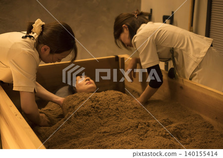 A woman entering an enzyme bath and a staff member assisting her. A woman entering an enzyme bath and a staff member assisting her. 140155414