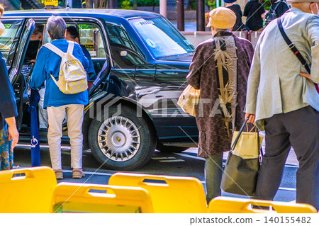Yokohama Station West Exit, a cityscape of Yokohama, Japan. An elderly woman with a cane gets into a taxi... For some reason, many people in Yokohama are wearing masks. Yokohama Station West Exit, a cityscape of Yokohama, Japan. An elderly woman with a cane gets into a taxi... For some reason, many people in Yokohama are wearing masks. 140155482