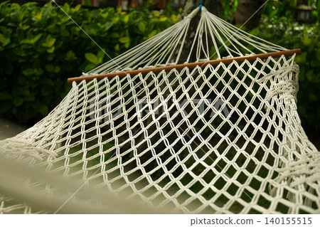 A hammock hangs between trees in a Bali garden, inviting rest A hammock hangs between trees in a Bali garden, inviting rest 140155515