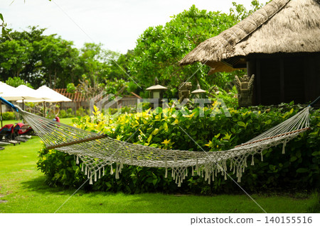 A hammock hangs between trees in a lush garden in Bali A hammock hangs between trees in a lush garden in Bali 140155516