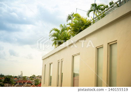 A building top has plants growing in Bali under a cloudy sky A building top has plants growing in Bali under a cloudy sky 140155519