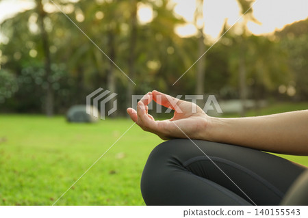 Person meditating in a Bali garden with lush plants around 140155543