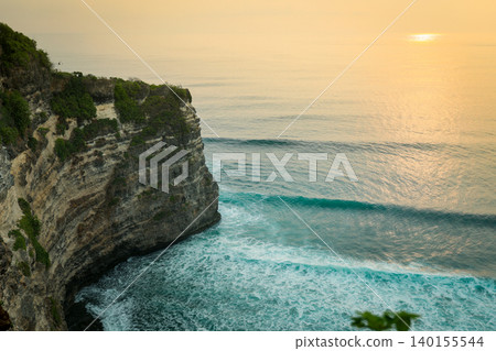 Waves crash against the cliffs as the sun sets over Bali 140155544