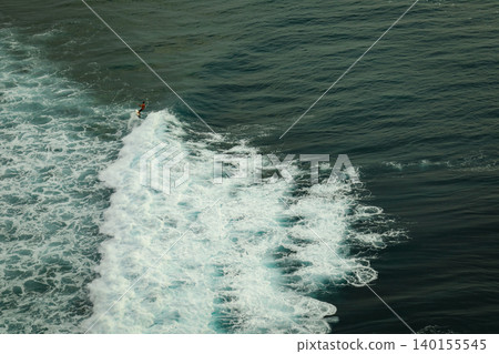 Surfer carves through ocean waves in Bali on a sunny day Surfer carves through ocean waves in Bali on a sunny day 140155545