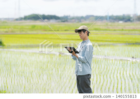 A young man uses a tablet to farm. A young man uses a tablet to farm. 140155813