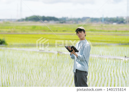 A young man uses a tablet to farm. A young man uses a tablet to farm. 140155814